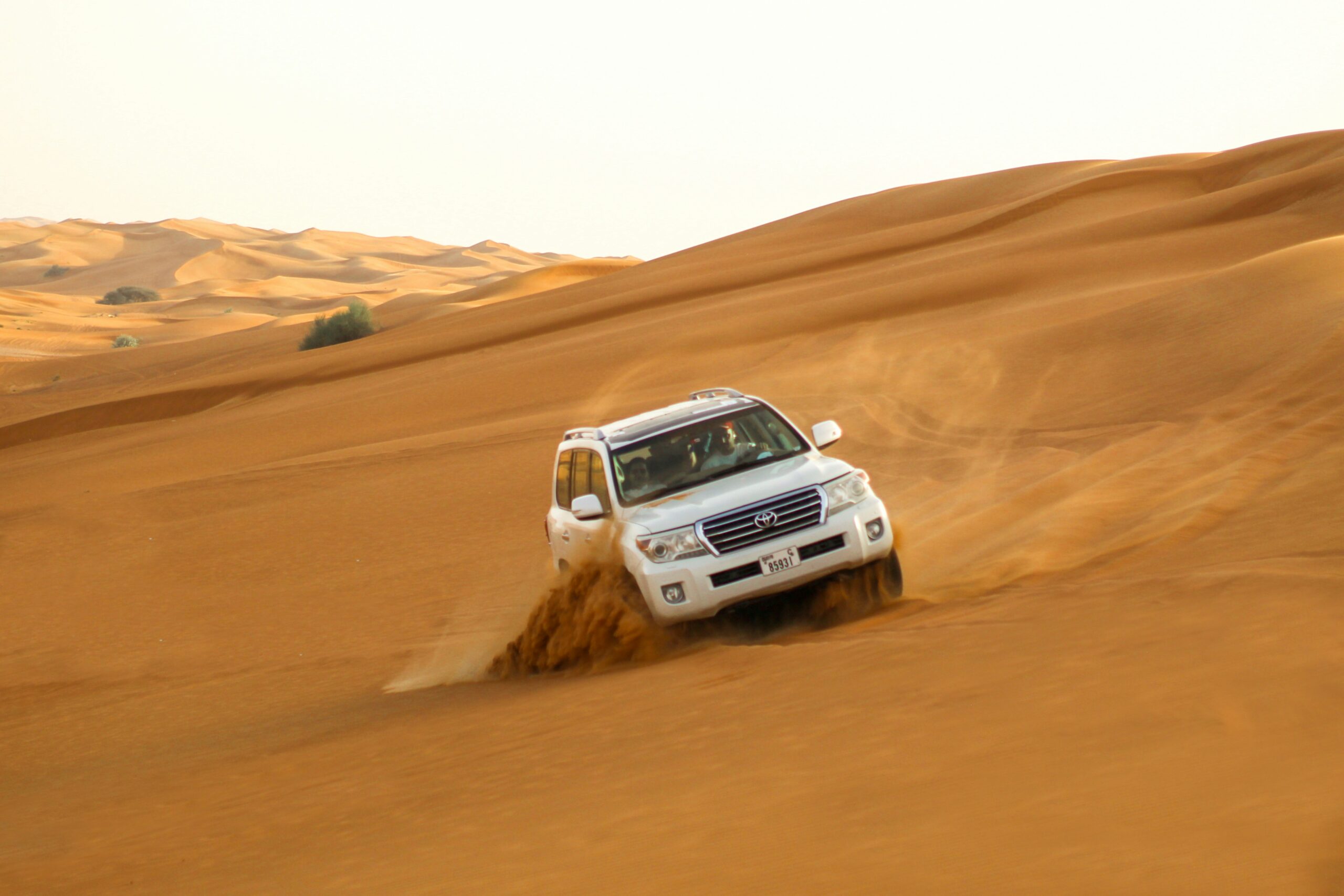 4 multiply 4 SUV dashing through sand dunes during premium desert safari in Dubai.